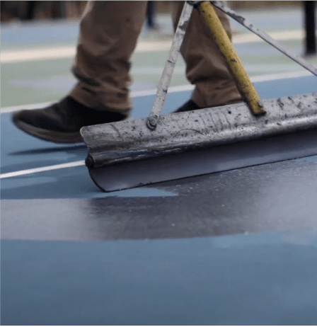 Close-up image of a CourTex employee resurfacing a pickleball court, applying smooth, durable coating for optimal play.