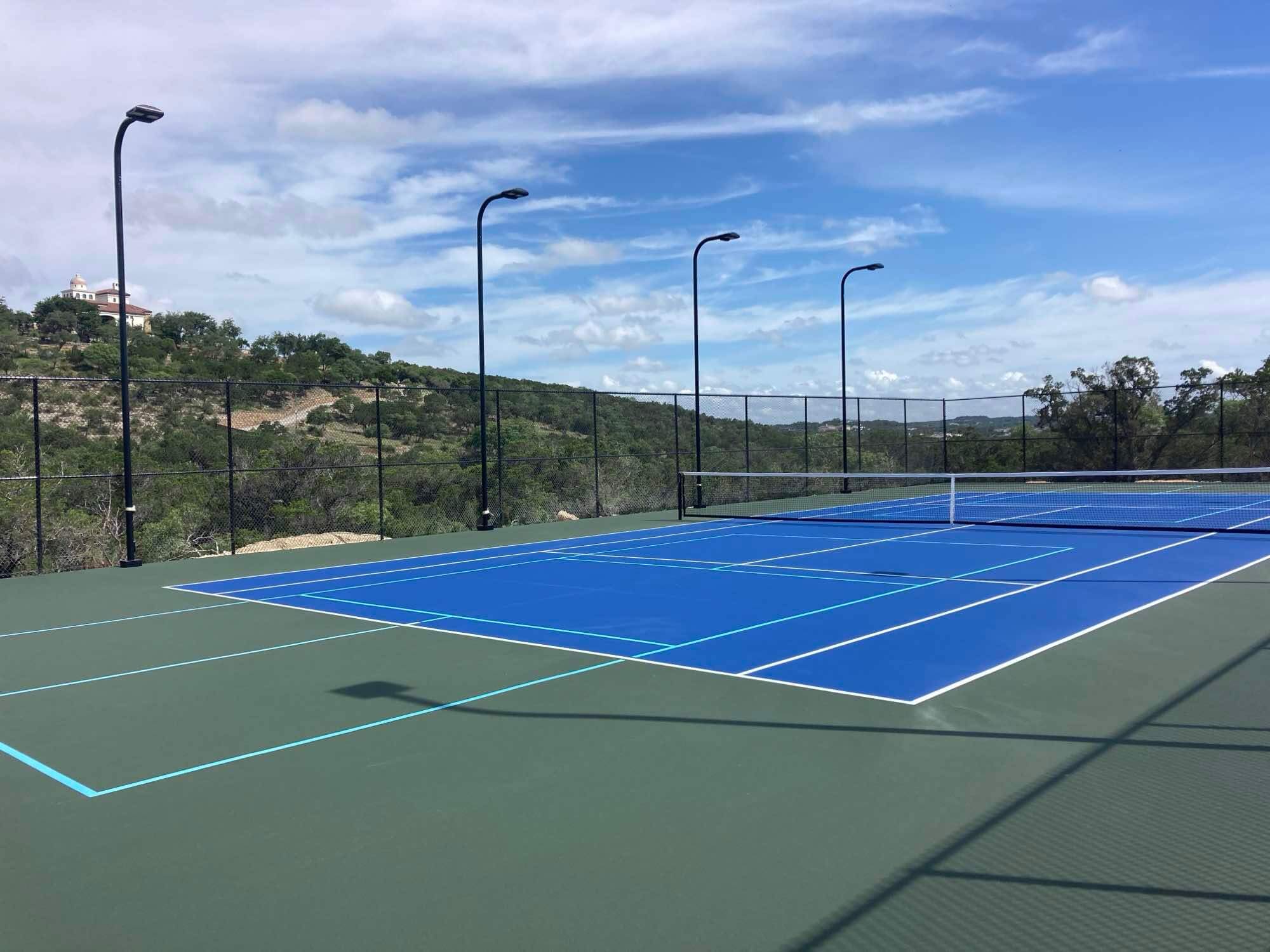 Private backyard pickleball court with vibrant blue and green coloring and durable netting.